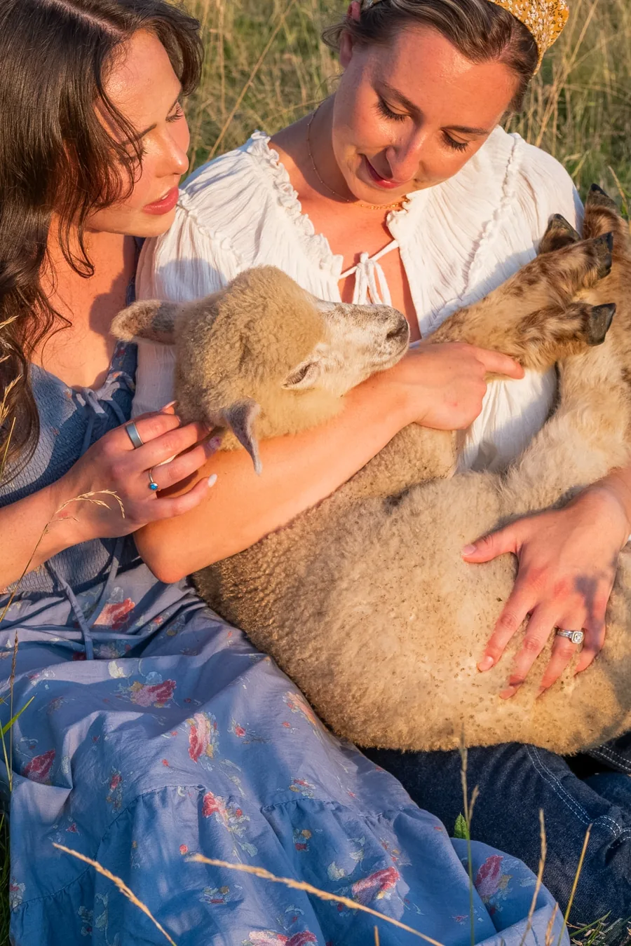 Two women holding a lamb in the 2027 Lead Me photoshoot